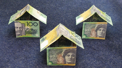 3 houses made of $100 notes